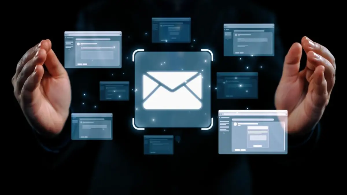 A close-up of a person’s hands gesturing towards a glowing email icon surrounded by floating interface windows, symbolizing digital communication.