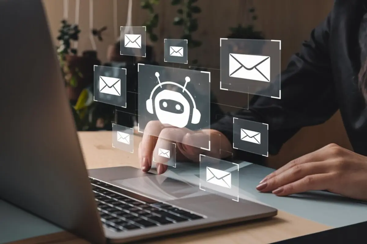 A person interacts with a laptop while digital icons of emails and a chatbot overlay the scene, suggesting communication automation.