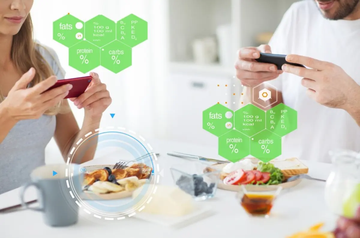 Two people at a table analyzing their meals using smartphones, with nutrition data displayed in hexagonal graphics.