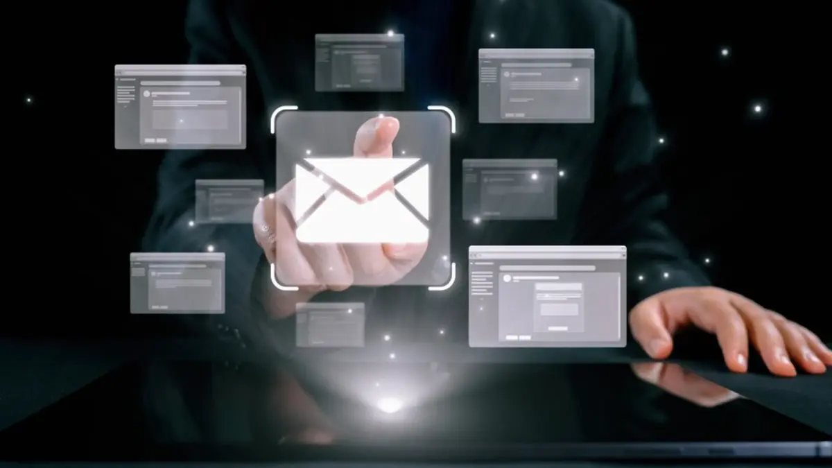 A suited man uses a touchscreen to interact with floating email icons and application windows, symbolizing digital communication.