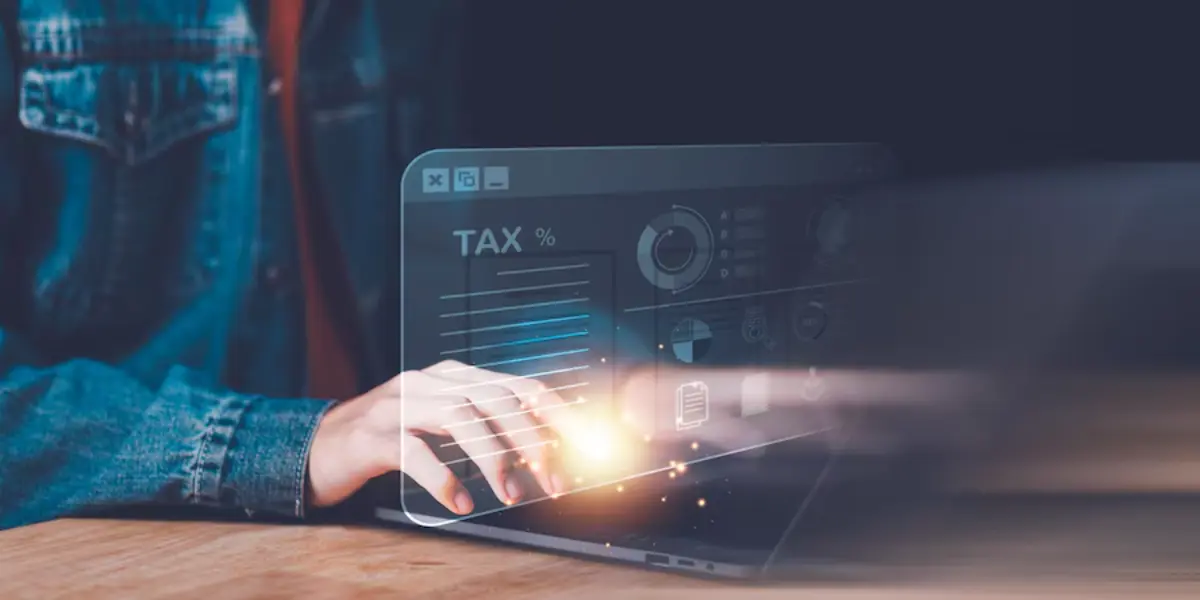A person typing on a laptop with a digital overlay displaying tax data and charts, symbolizing online tax preparation.