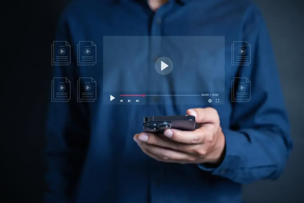 A person in a blue shirt holds a smartphone displaying a video player and file icons, suggesting interaction with media content.